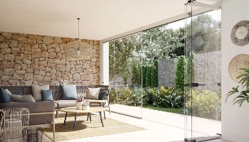 Cortinas de cristal instaladas en terraza cubierta, cerramiento transparente que integra jardín y zona de estar